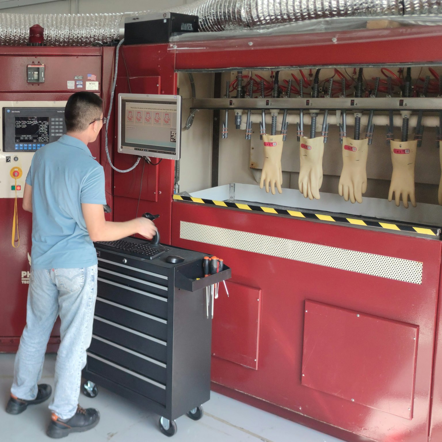 Homme devant l'ordinateur de contrôle d'une machine de test de gants au sein du Service center du Groupe à Singapour