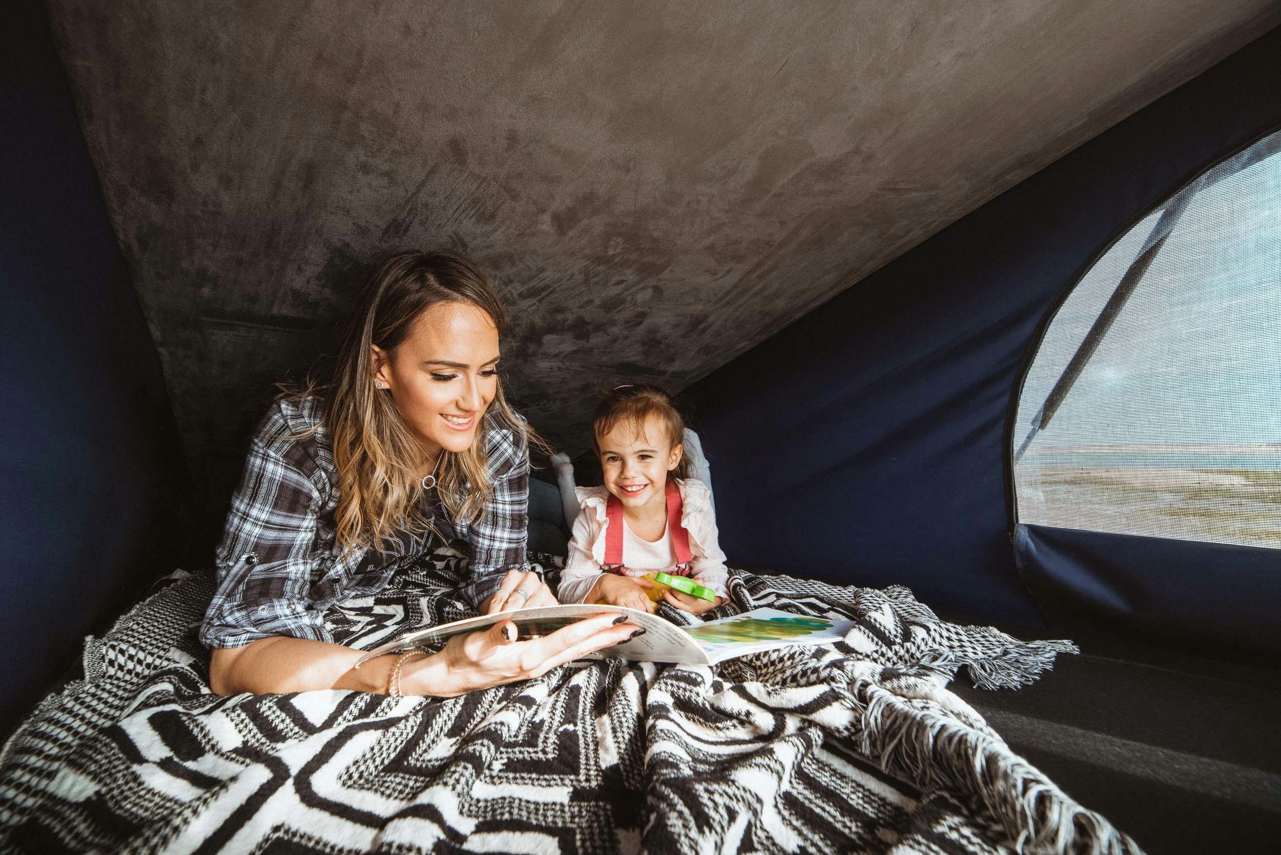 Mother and daughter relaxing in the camper pop up roof sleeping area.