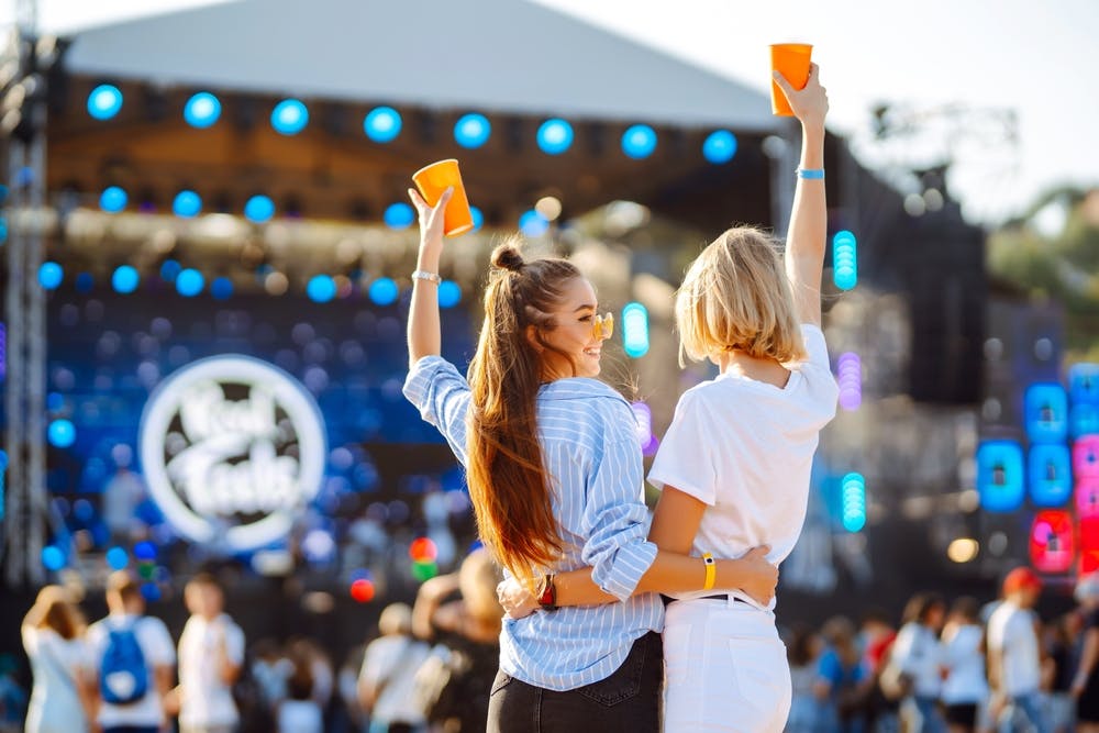 two friends enjoying a beer at a music festival