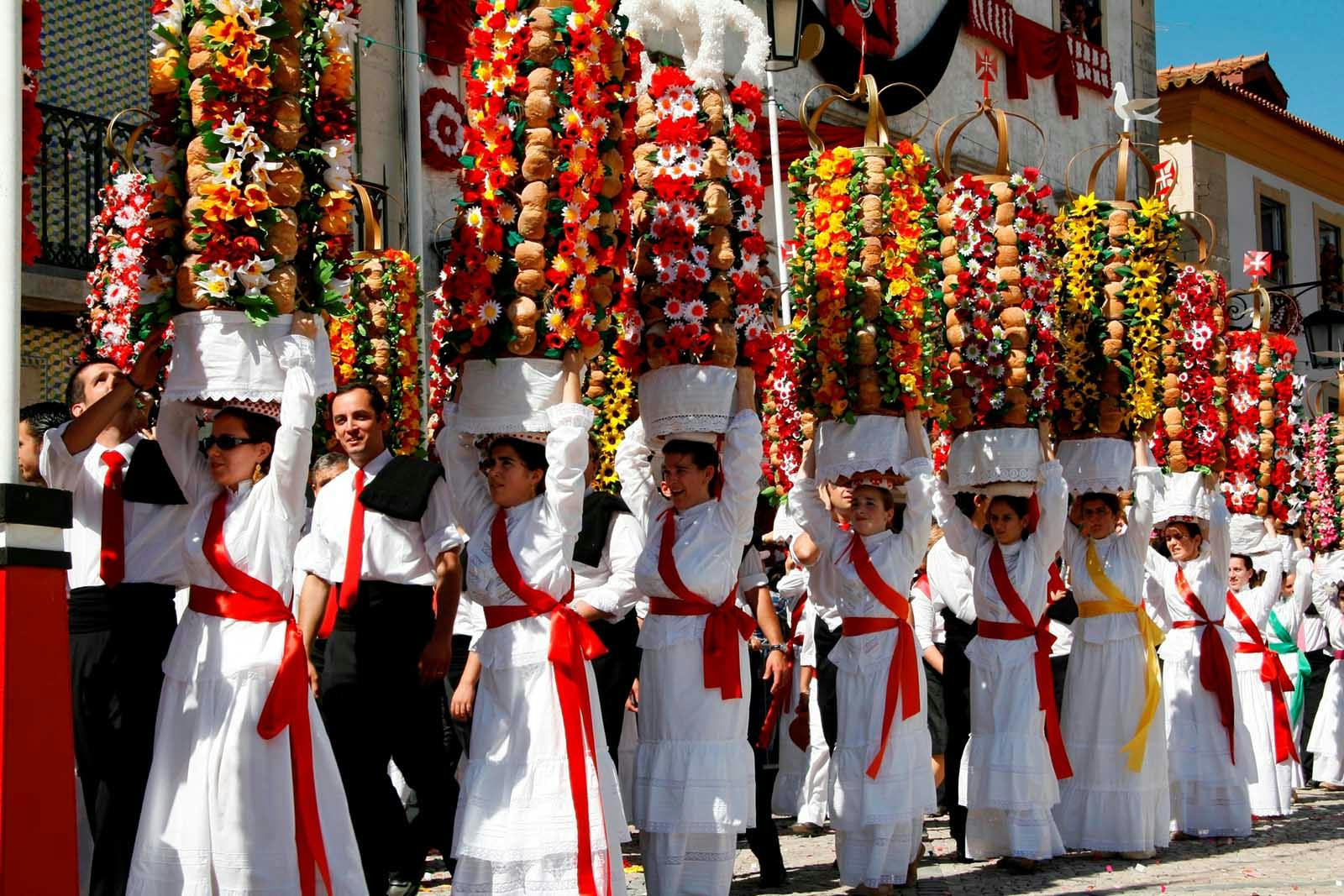 Elegant women parading with flower trays on their heads at the Festival of the Trays in Tomar, Portugal.