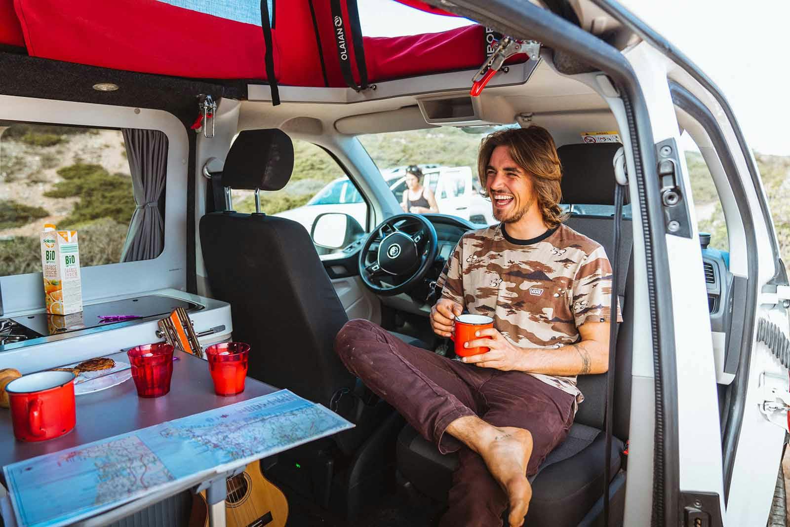 Surfer relaxing in the Siesta Beach campervan after a day of learning to surf in Portugal.