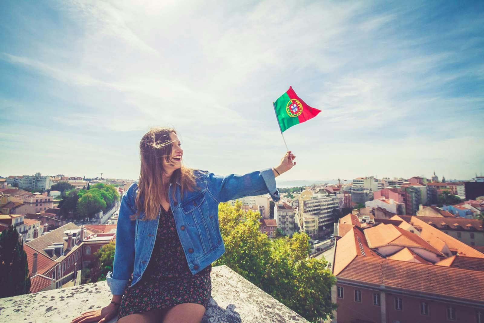 Woman holding up a small Portuguese flag during Portugal Day celebrations.