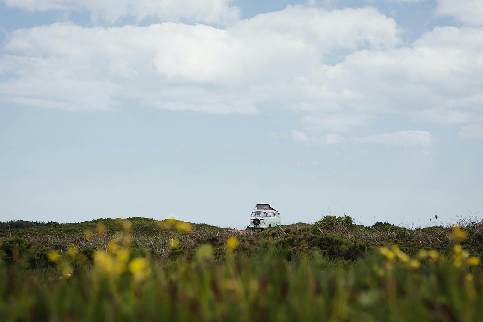 Campervan at a wild camp site in Portugal surrounded by beautiful flowers.