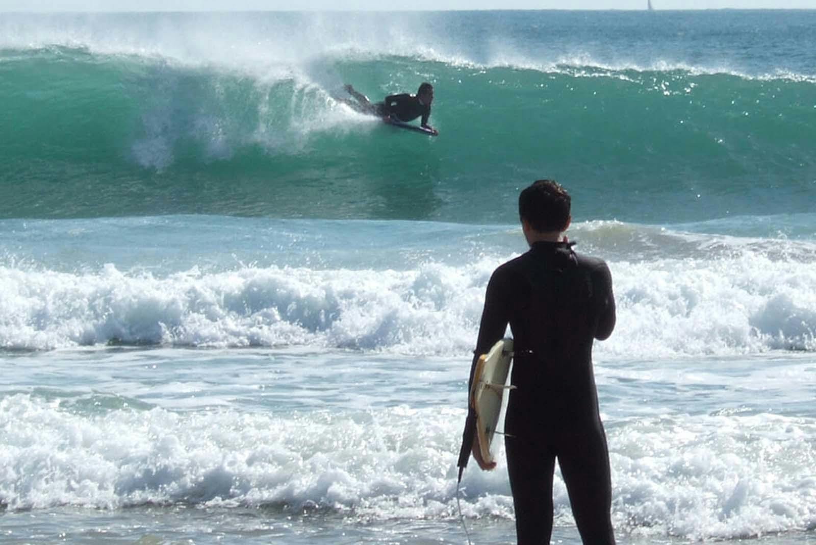 Surfeur regardant les vagues de Figueira da Foz depuis le rivage.