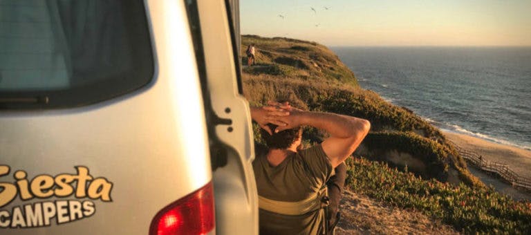 Camper enjoying a sunset view over a rugged cliff on the Portuguese coast.