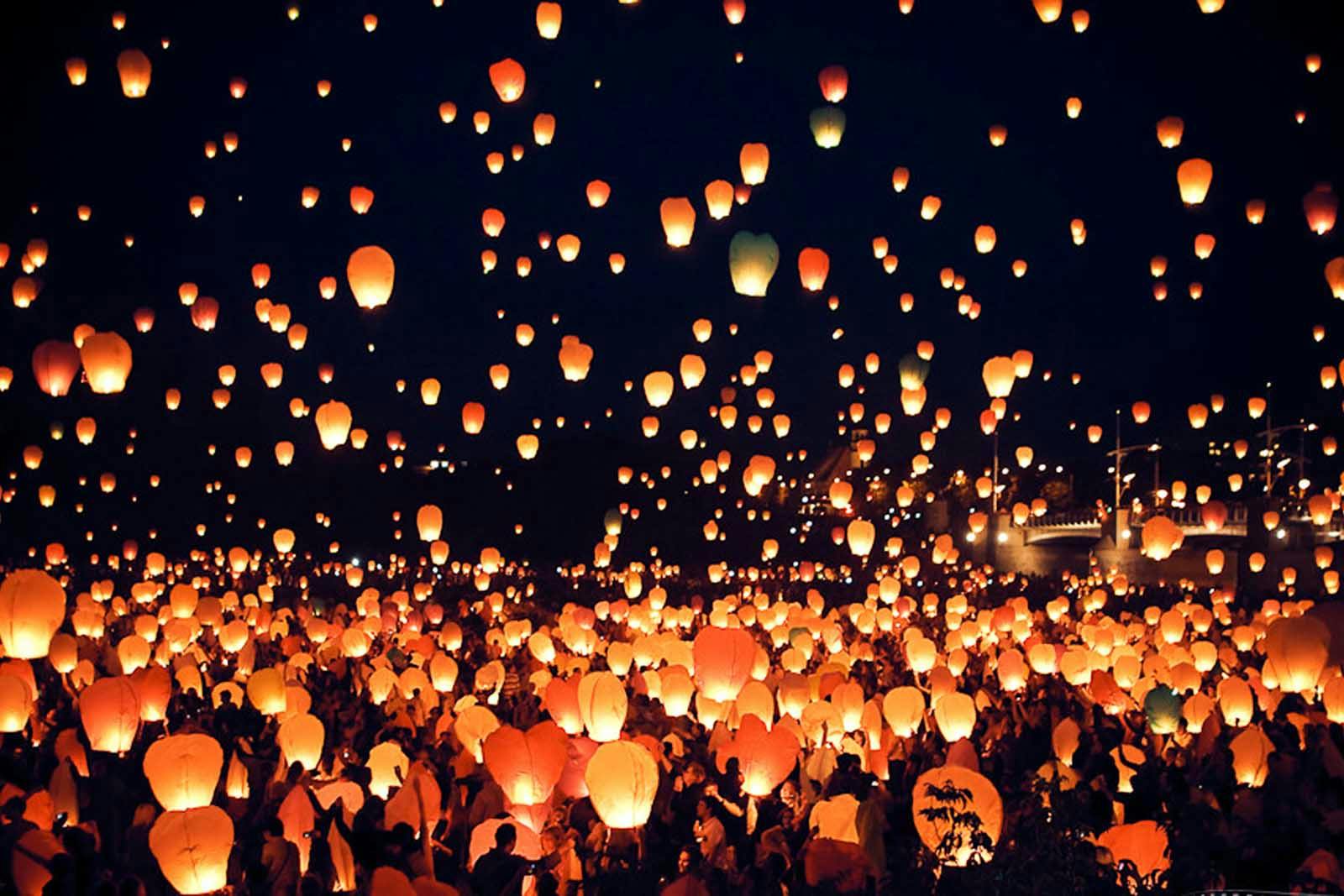 Pessoas acendendo lanternas à noite durante Festa de São João.