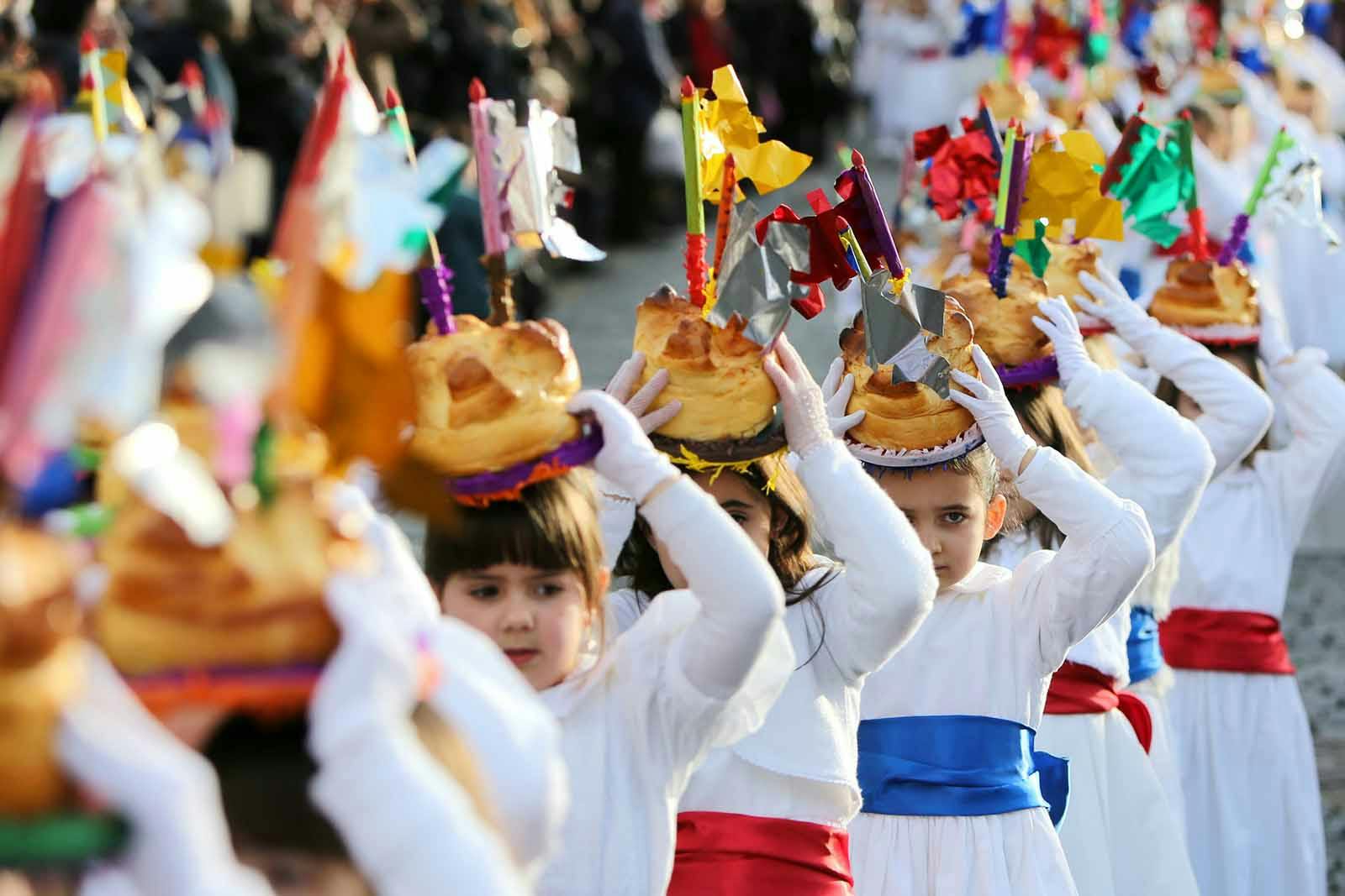 Young girls parading with fogaça cakes on their heads.