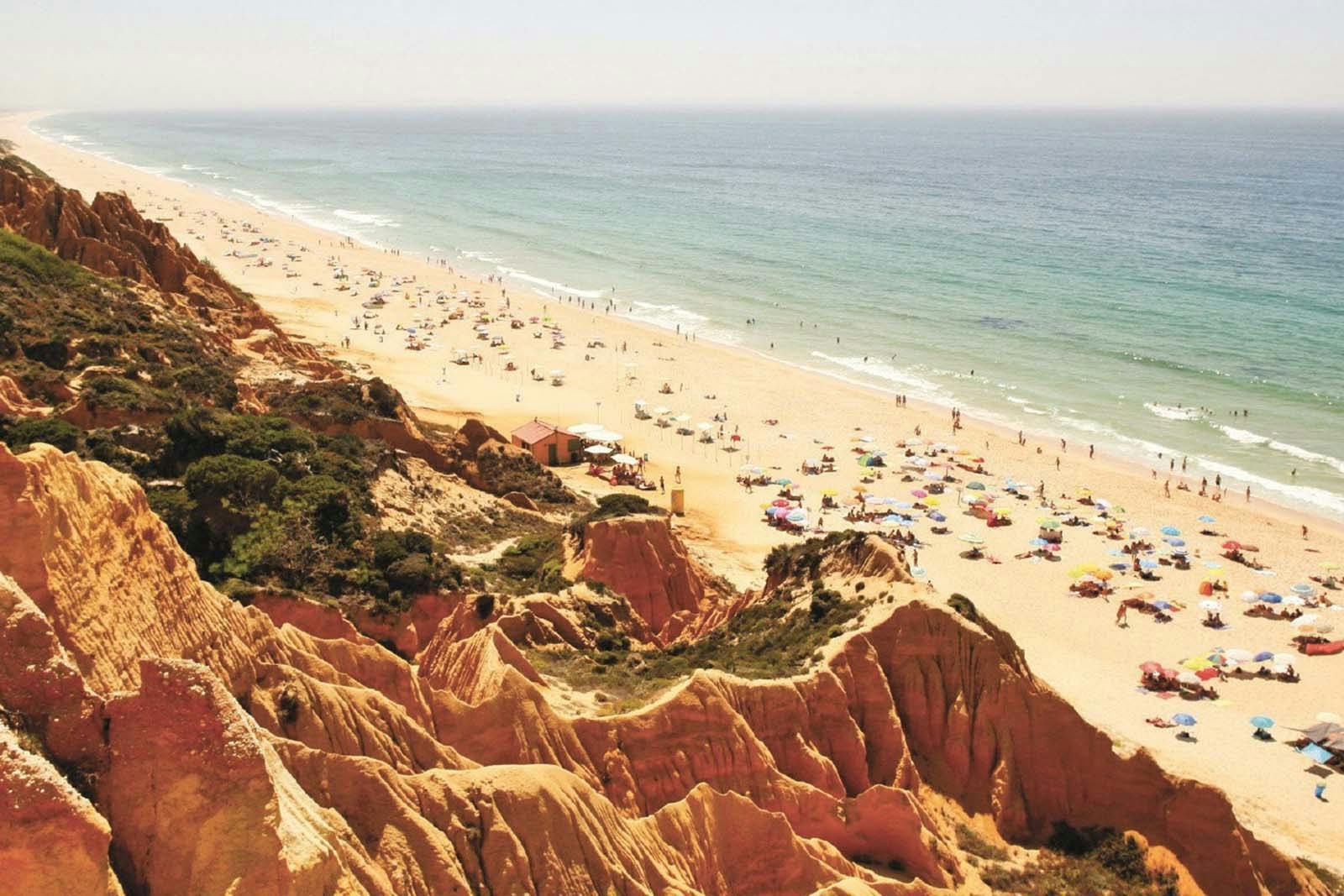 Praia da Gale with a view of the orange cliffs and the Atlantic coast near a campground.