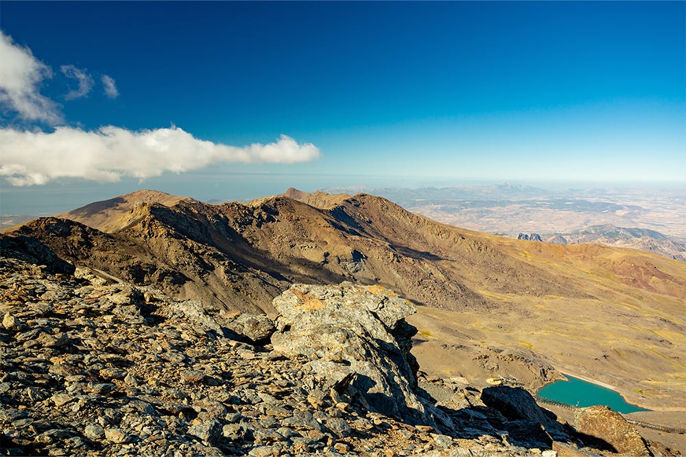 O popular cume da Serra Nevada, o Pico Veleta, ergue-se ao longe sob um céu azul.