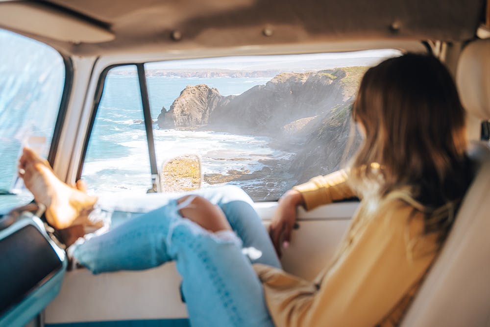 A woman waits in the passenger seat for assistance after finding her campervan with a flat battery. 