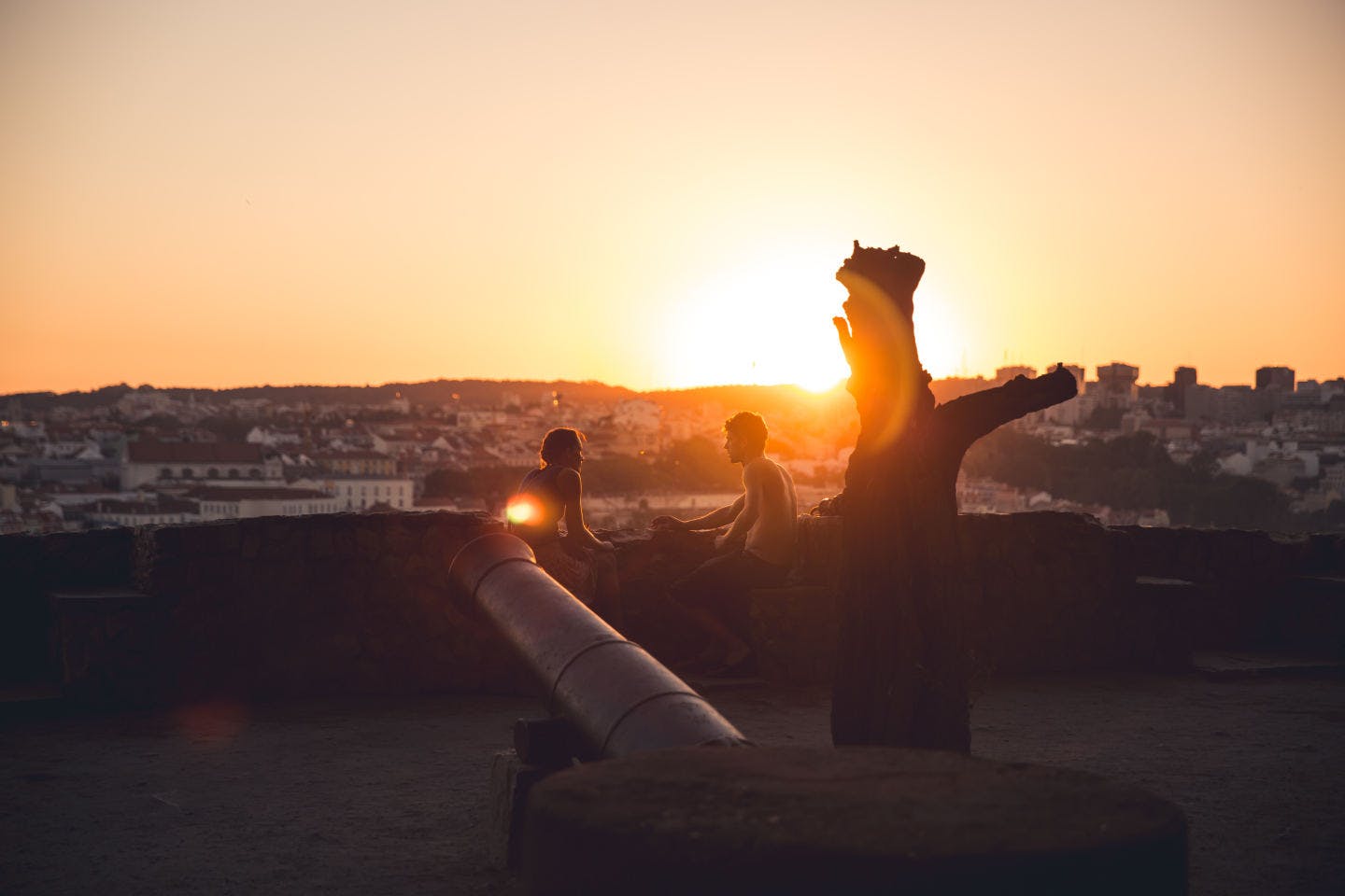 Pareja viendo como el sol se pone en el horizonte en Lisboa, Portugal.