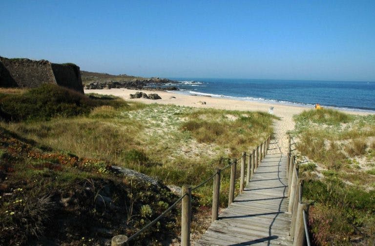 Wooden walkway leading to a sandy beach in Portugal.
