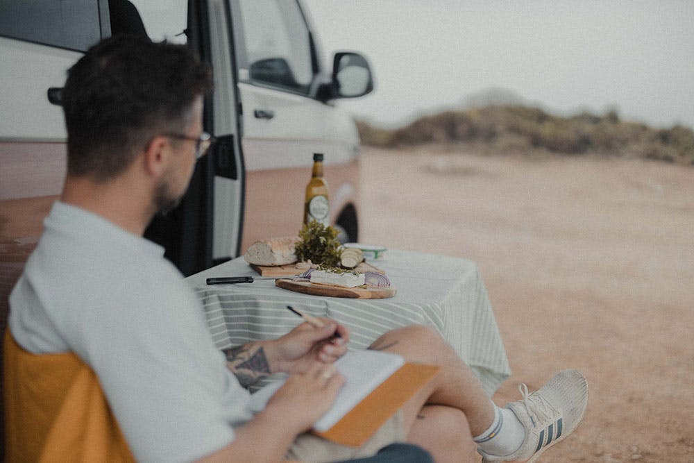 Hombre escribiendo en su diario en sus vacaciones sostenibles