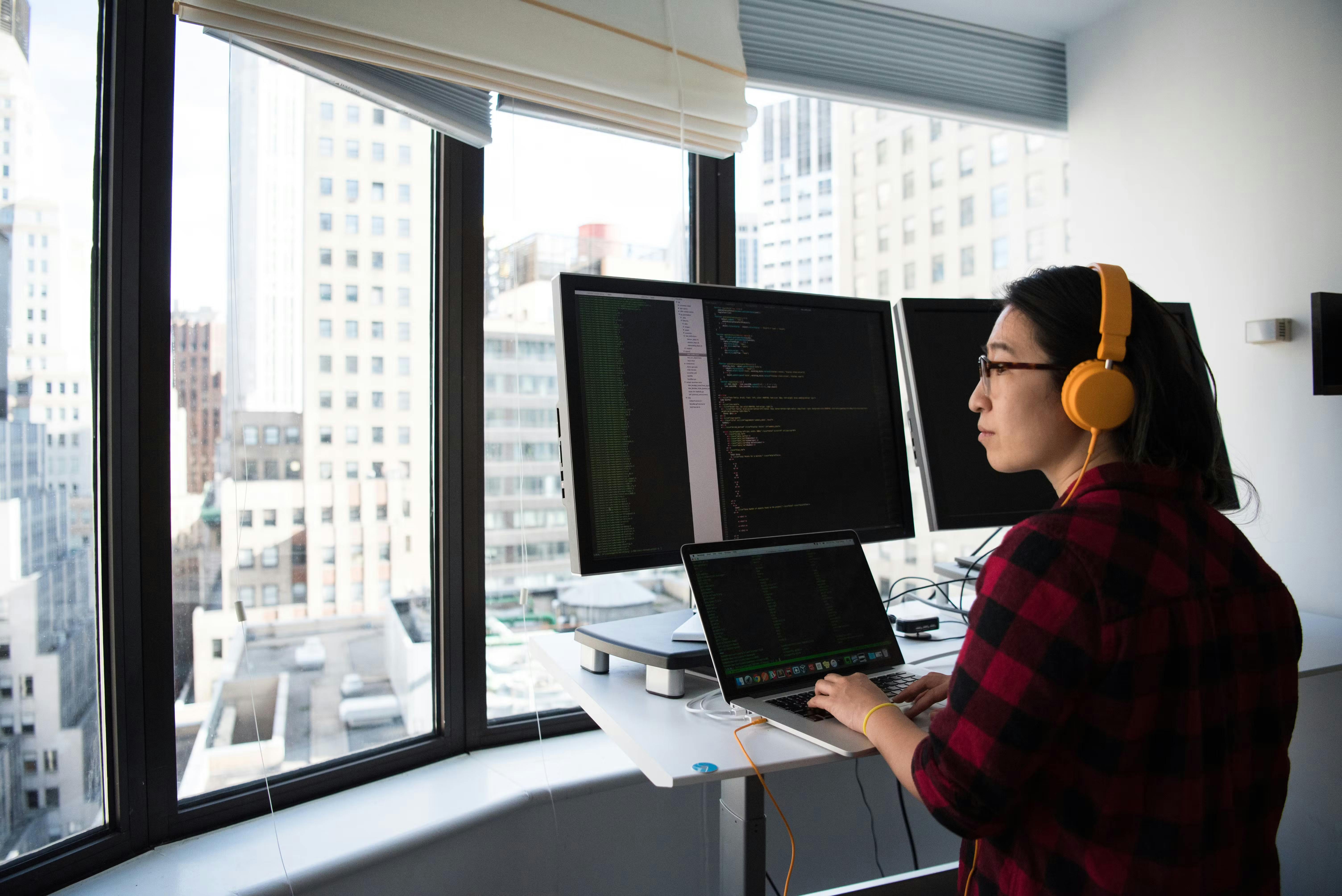 A woman looking out the window while sitting in front of a table, taking on a coding bootcamp