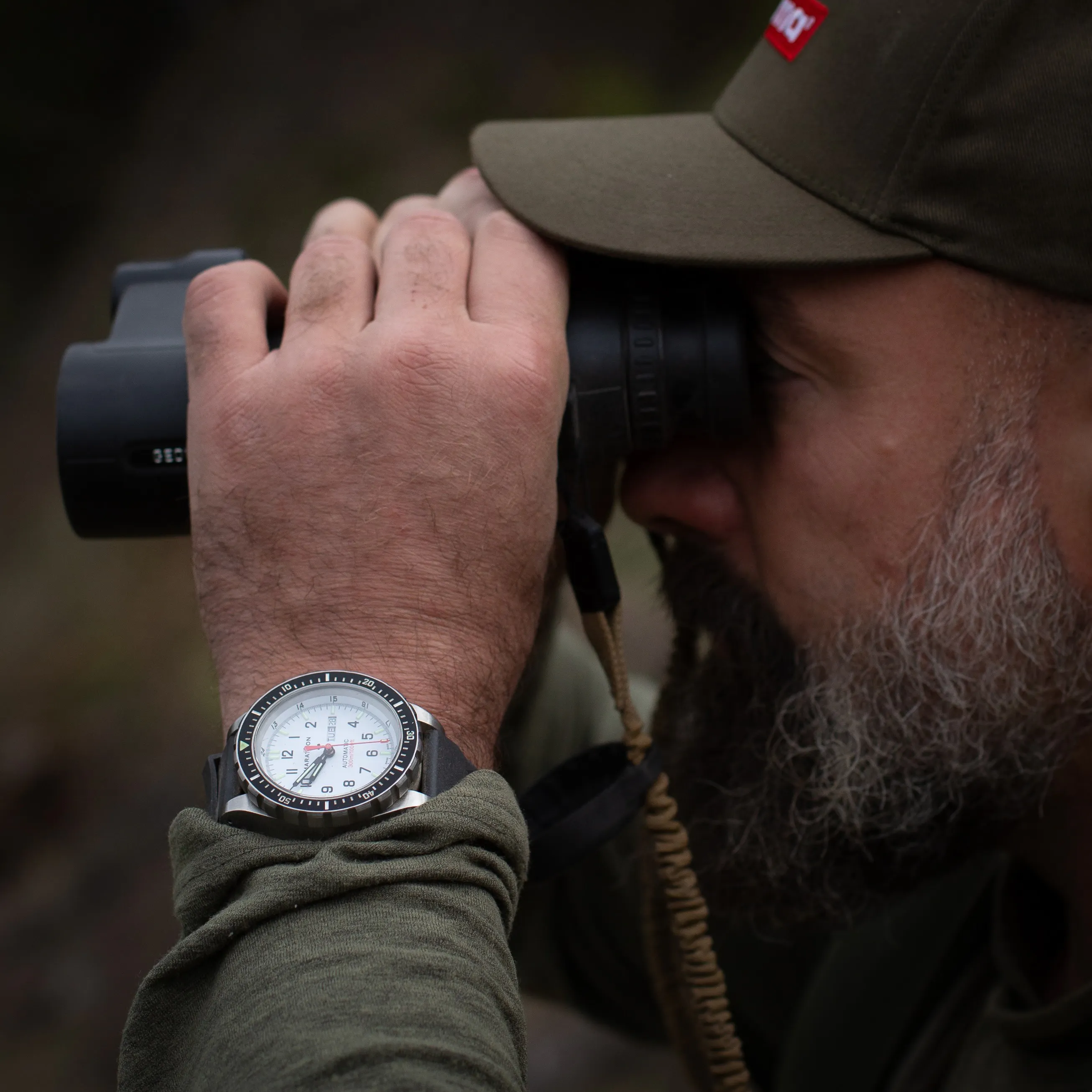 Travis Bader looking through binoculars wearing a Marathon Watch 46mm JDD Arctic