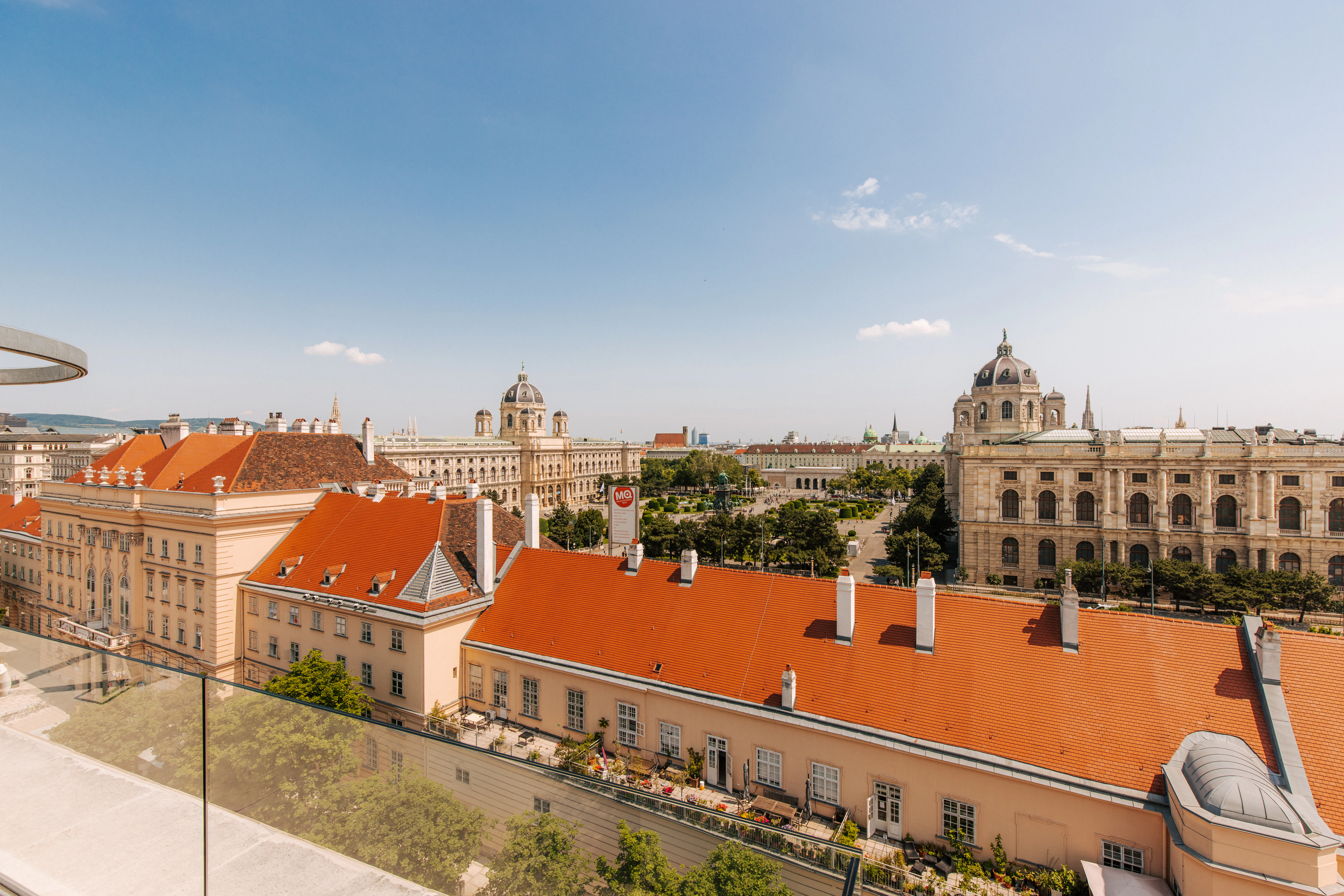 Blick über die historischen Dächer der Wiener Innenstadt mit klassischen Gebäuden und Kirchtürmen unter blauem Himmel.