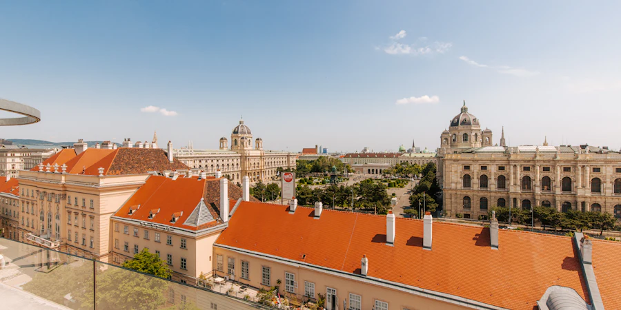 Blick über die historischen Dächer der Wiener Innenstadt mit klassischen Gebäuden und Kirchtürmen unter blauem Himmel.