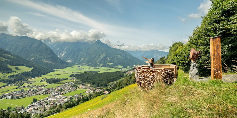 Das Bild zeigt eine ruhige Hanglage mit weitem Blick über grüne Täler und sanfte Berglandschaften. Eine Terrasse mit Sitzbereich lädt zum Entspannen ein und vermittelt ein Gefühl von Freiheit, Natur und exklusiver Wohnqualität.