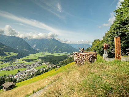 The image shows a quiet hillside location with wide views over green valleys and gentle mountain landscapes. A terrace with a seating area invites you to relax and conveys a sense of freedom nature and exclusive living quality.