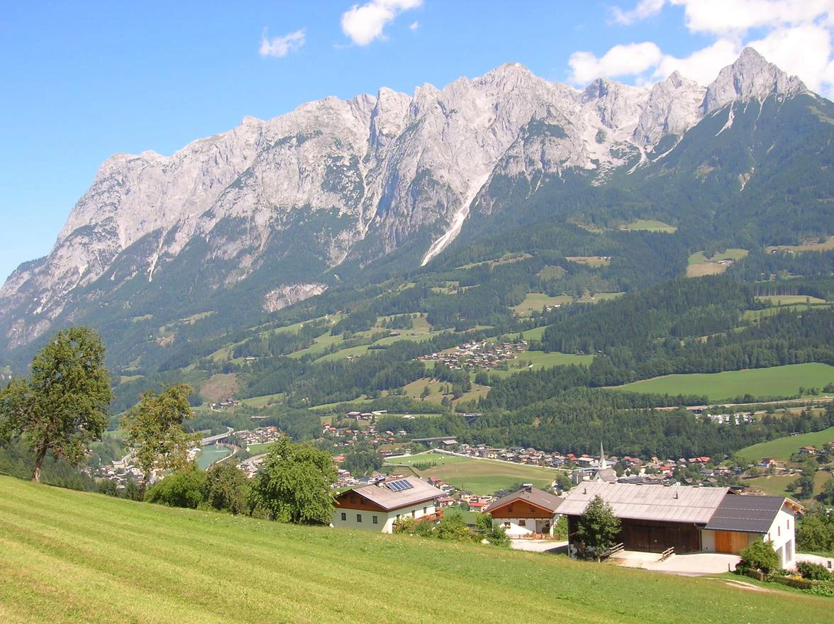 Idyllische Alpenlandschaft mit saftig grünen Wiesen, vereinzelten Häusern und beeindruckender Bergkulisse – ruhig, naturnah und mit hoher Lebensqualität.