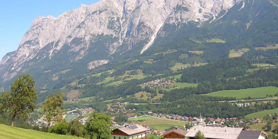 Idyllische Alpenlandschaft mit saftig grünen Wiesen, vereinzelten Häusern und beeindruckender Bergkulisse – ruhig, naturnah und mit hoher Lebensqualität.