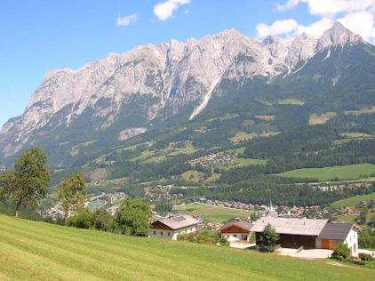Idyllische Alpenlandschaft mit saftig grünen Wiesen, vereinzelten Häusern und beeindruckender Bergkulisse – ruhig, naturnah und mit hoher Lebensqualität.