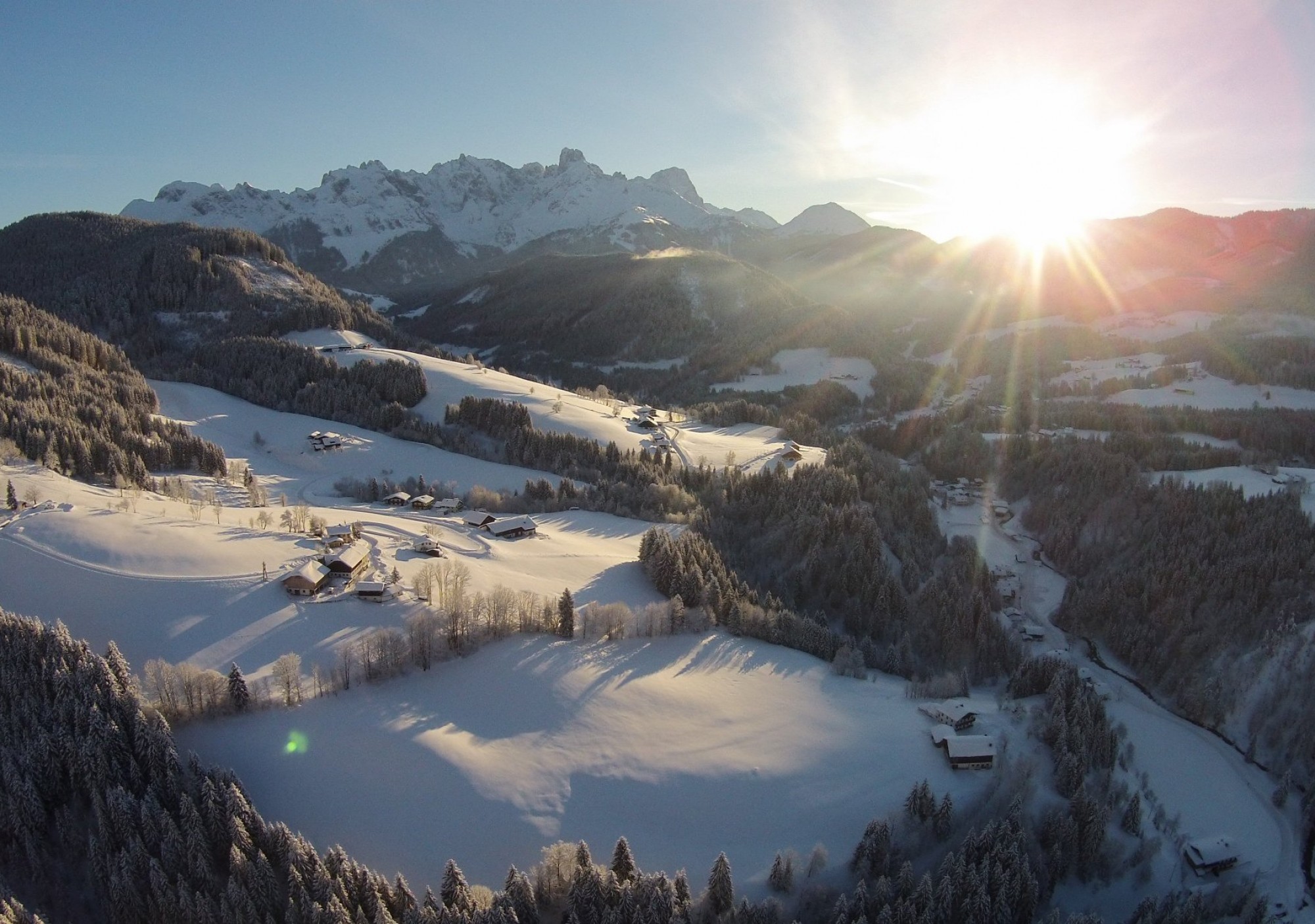 Ein winterlicher Bergsee, umgeben von schneebedeckten Hängen, im warmen Licht der tief stehenden Sonne – ruhig, klar und beeindruckend.