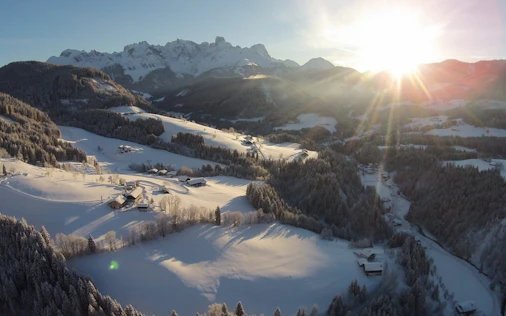 Ein winterlicher Bergsee, umgeben von schneebedeckten Hängen, im warmen Licht der tief stehenden Sonne – ruhig, klar und beeindruckend.