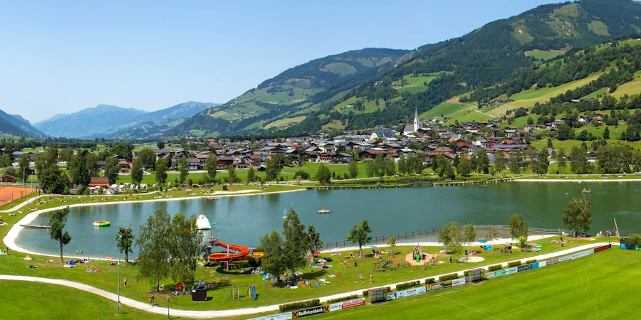 An idyllic lake nestled in a green landscape with views of gentle hills and mountains, complemented by well-maintained paths and a calm, inviting atmosphere.