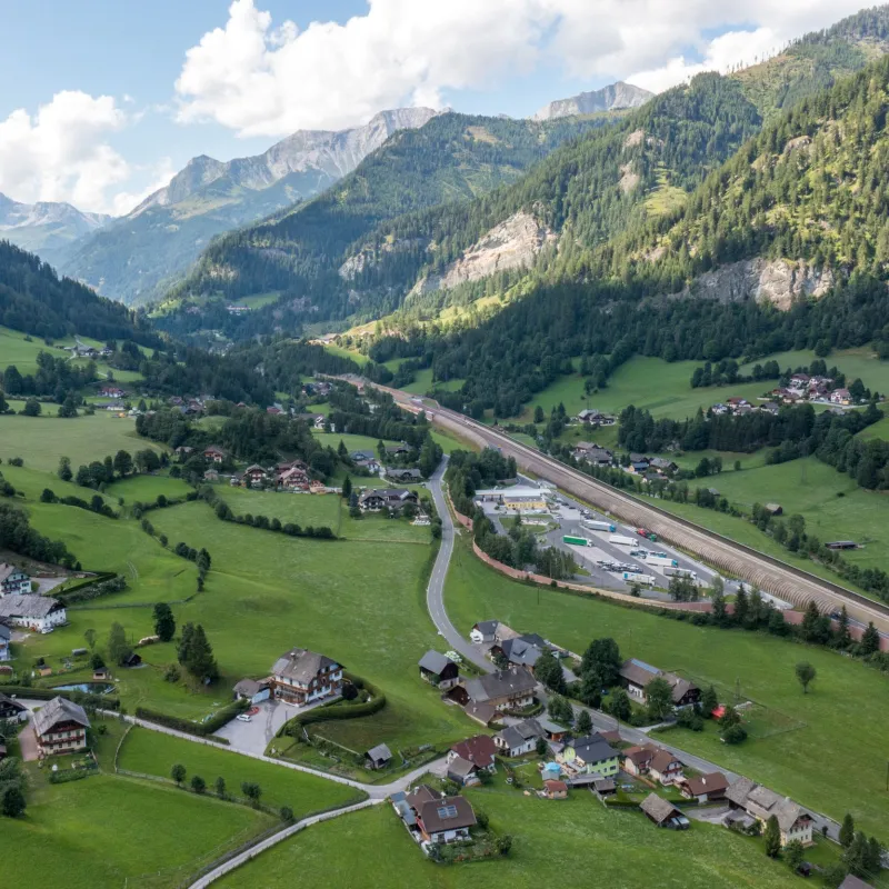 The image shows an idyllic valley in Zederhaus with wide meadows, scattered houses, and a road winding through the landscape. Surrounded by impressive mountains, it creates a calm, nature-oriented setting with a great sense of openness.