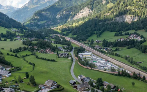 Das Bild zeigt ein idyllisches Tal in Zederhaus mit weitläufigen Wiesen, vereinzelten Häusern und einer Straße, die sich durch die Landschaft zieht. Umgeben von beeindruckenden Bergen entsteht ein ruhiges, naturnahes Gesamtbild mit viel Weitblick.