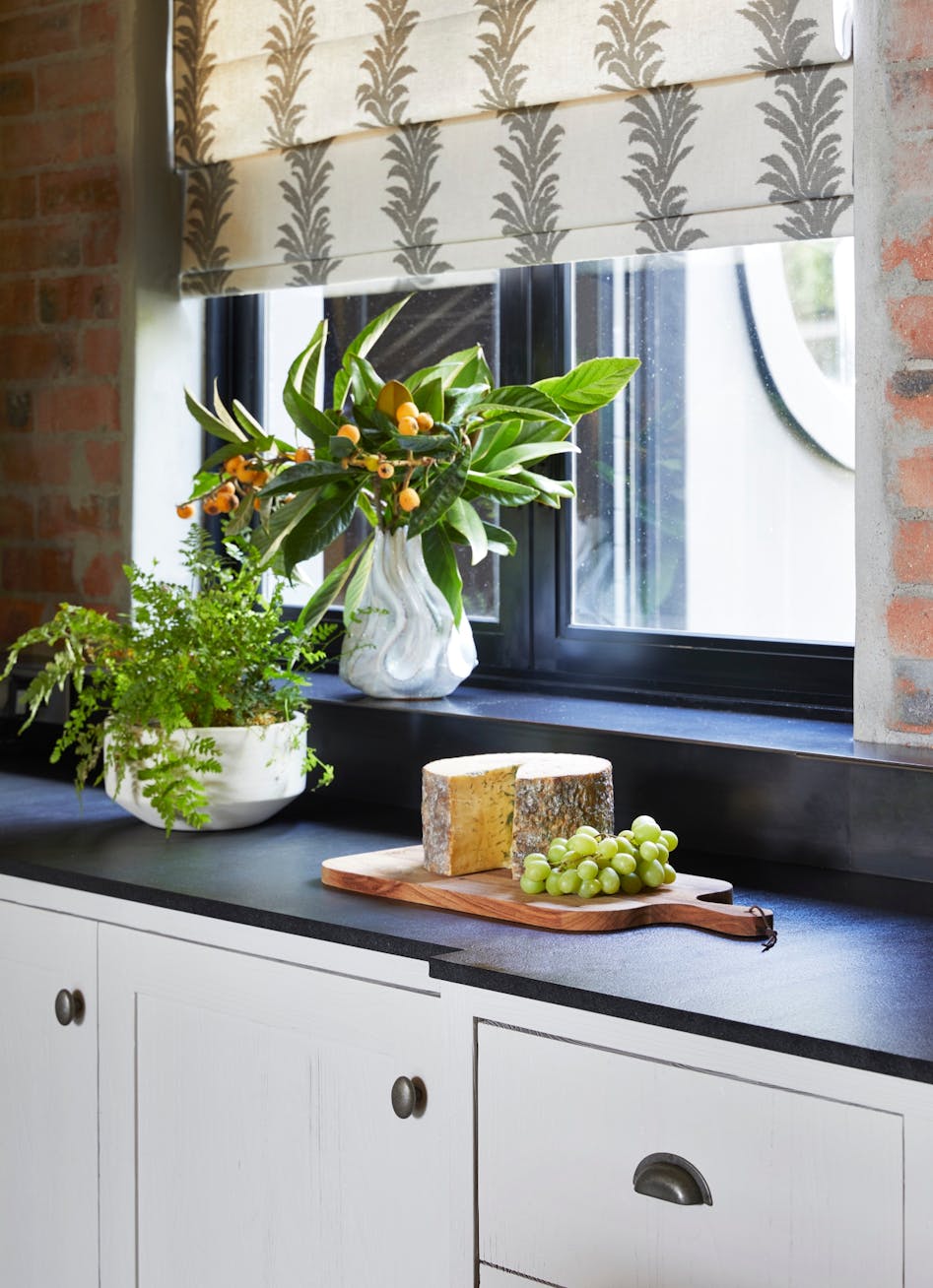 Close-up of a kitchen with dark blue cabinetry, a window with a view of the outdoors and a charcuterie board on the countertop.