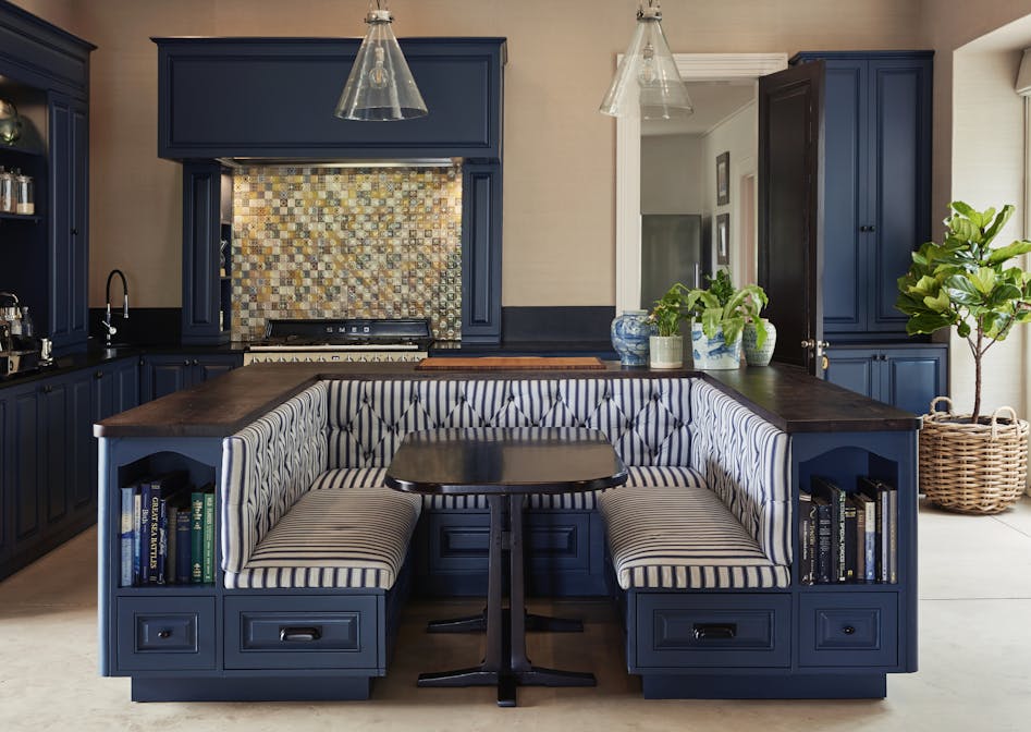 A kitchen banquette in a dark blue colour with a wooden top and black and white striped upholstery
