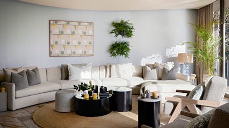 A contemporary living room with circular side and coffee tables on a round mat with a curved sofa against the back wall.