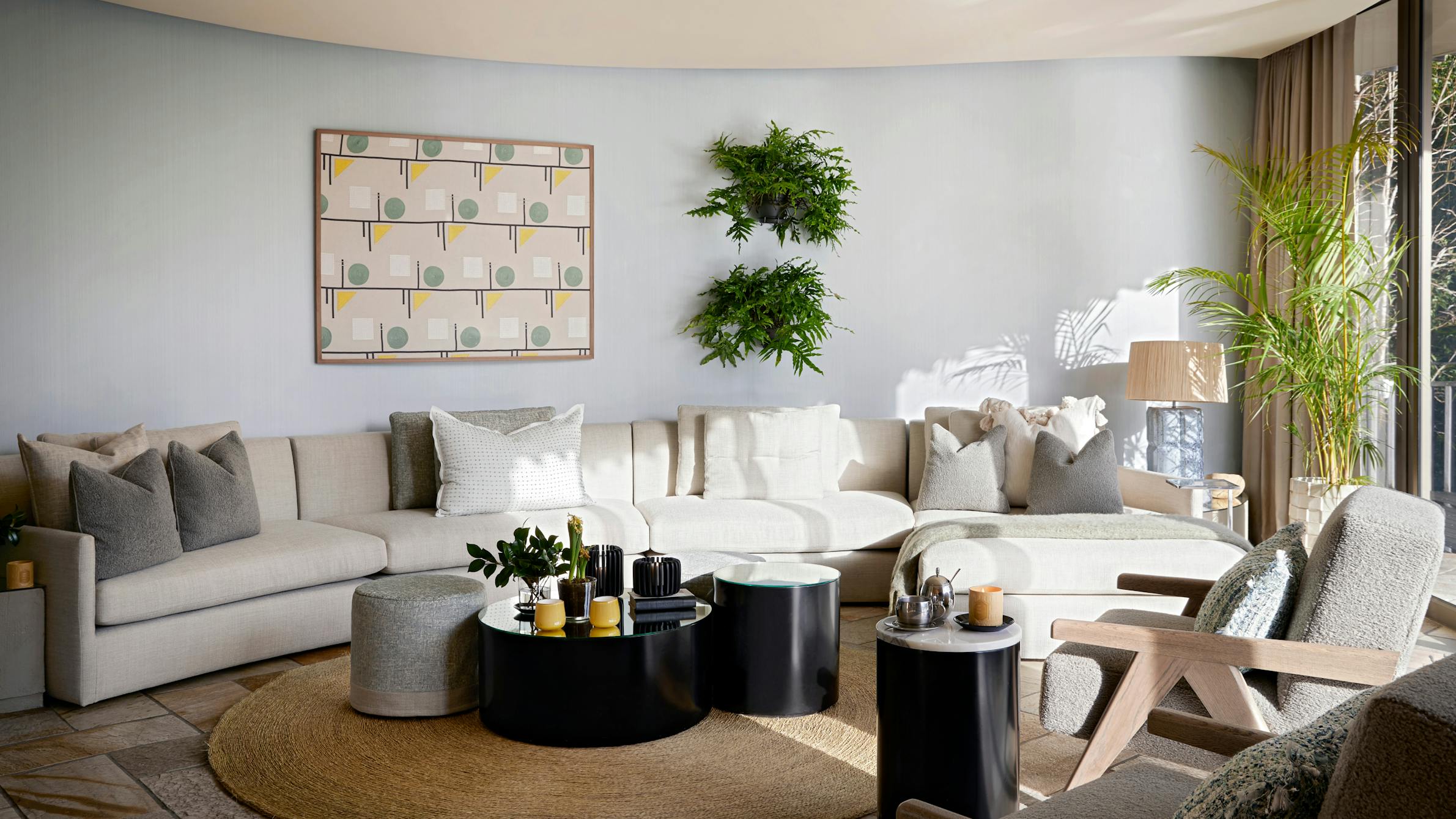 A contemporary living room with circular side and coffee tables on a round mat with a curved sofa against the back wall.