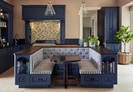 A kitchen banquette in a dark blue colour with a wooden top and black and white striped upholstery.
