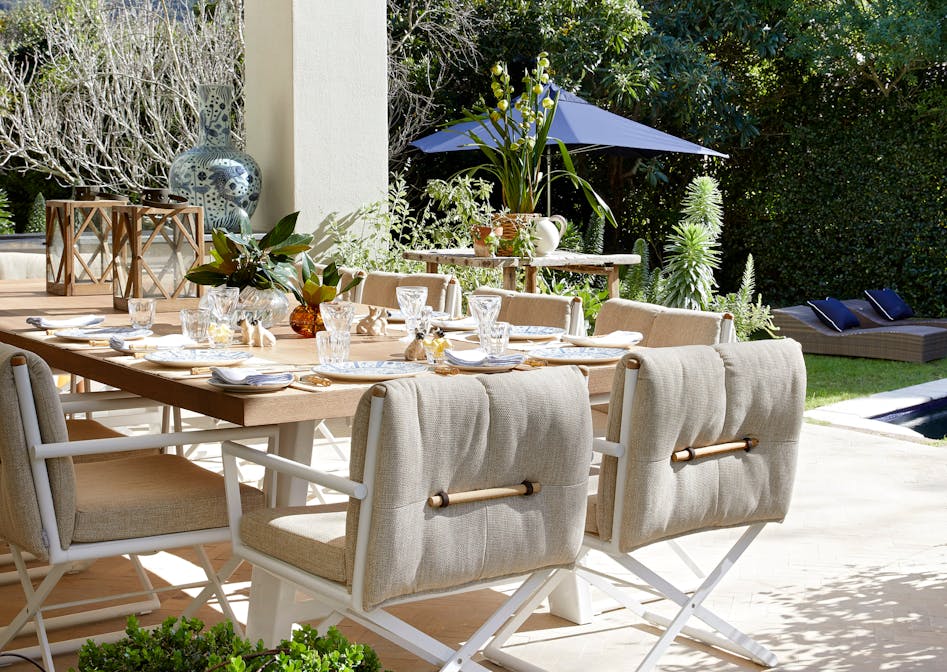 An outdoor dining area with views of a mountain in the background and a wooden dining table with modern chairs in the foreground.