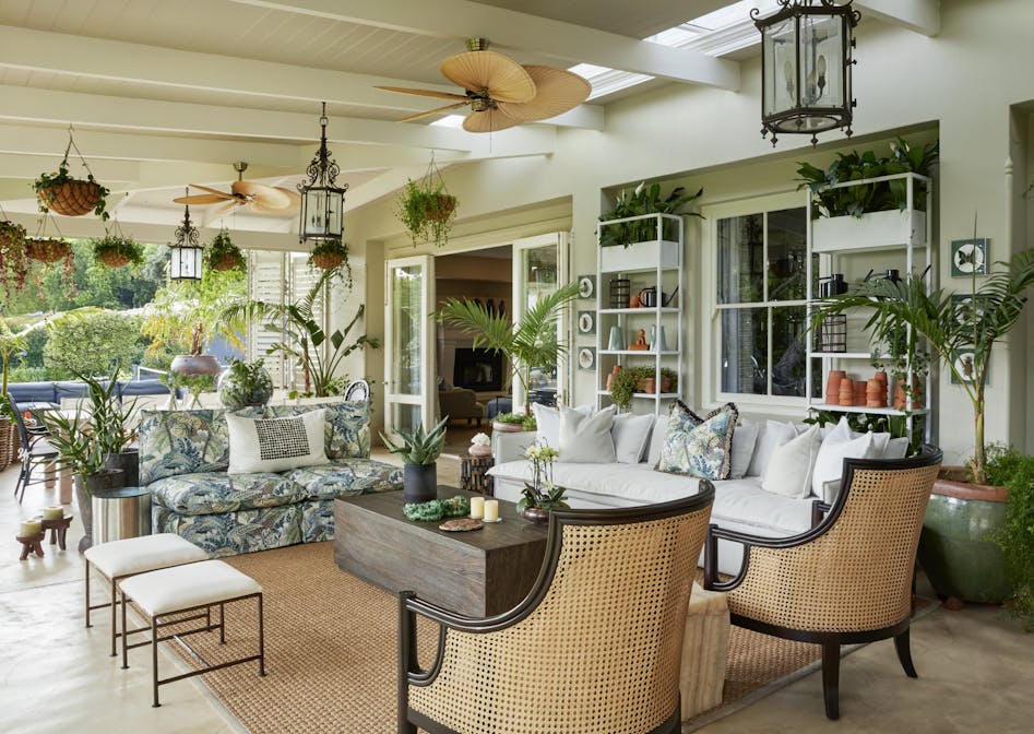 An outdoor entertainment area with a wooden coffee table in the middle, surrounded by two sofas and two rattan armchairs.