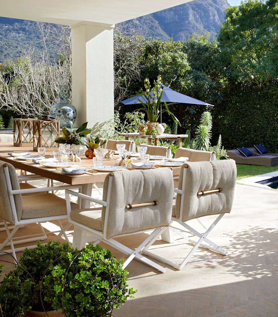 An outdoor dining area with views of a mountain in the background and a wooden dining table with modern chairs in the foreground.