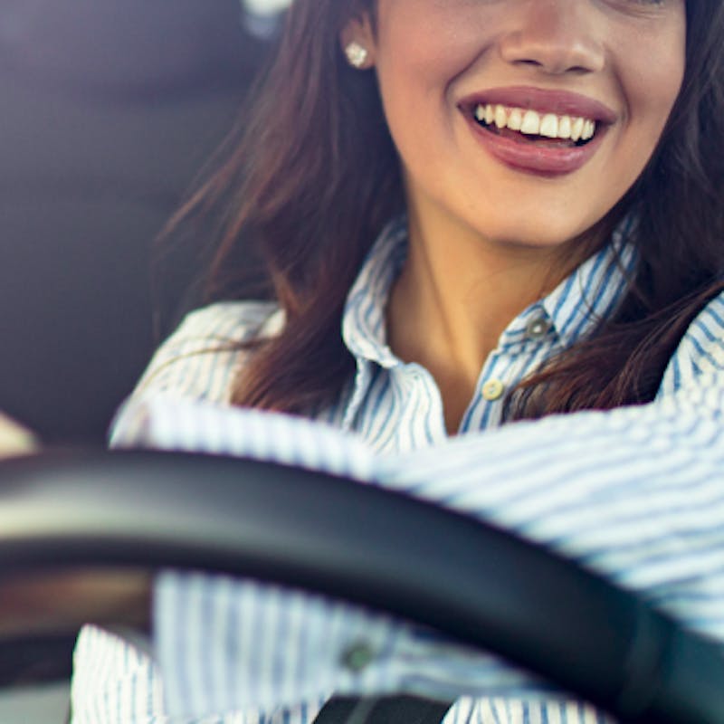 mulher branca sorrindo enquanto dirige