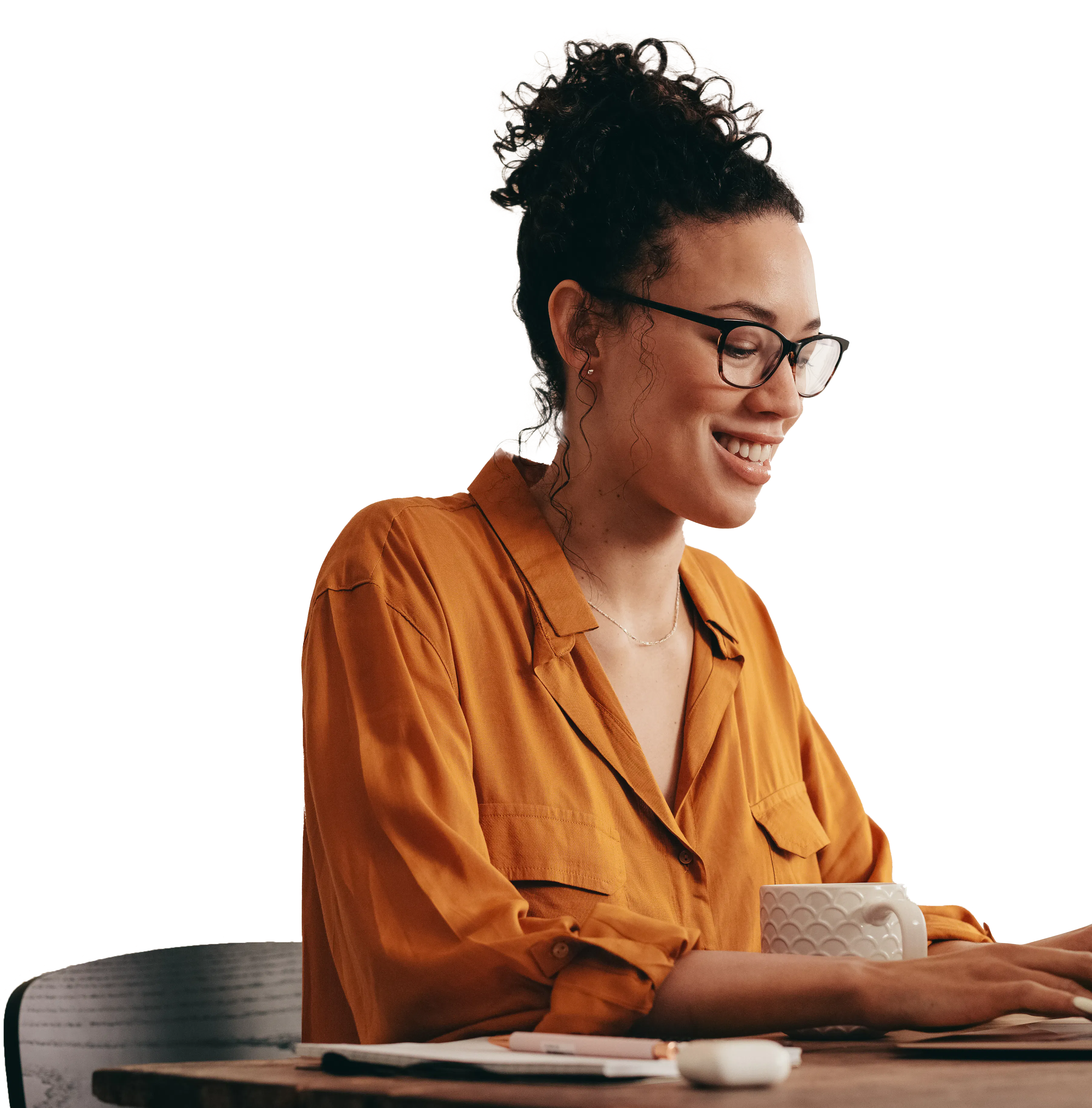 Mulher trabalhando em um computador com uma xícara de café e um caderno de anotações ao lado