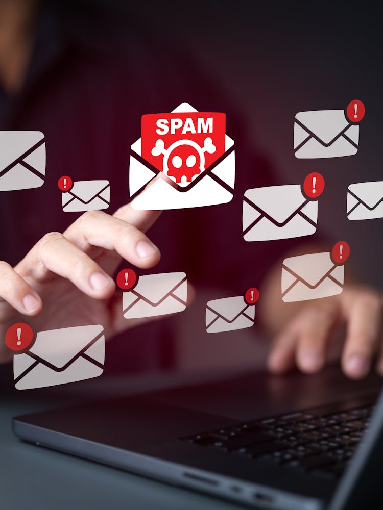 A person at their computer, confronted by email spam, phishing emails and malware