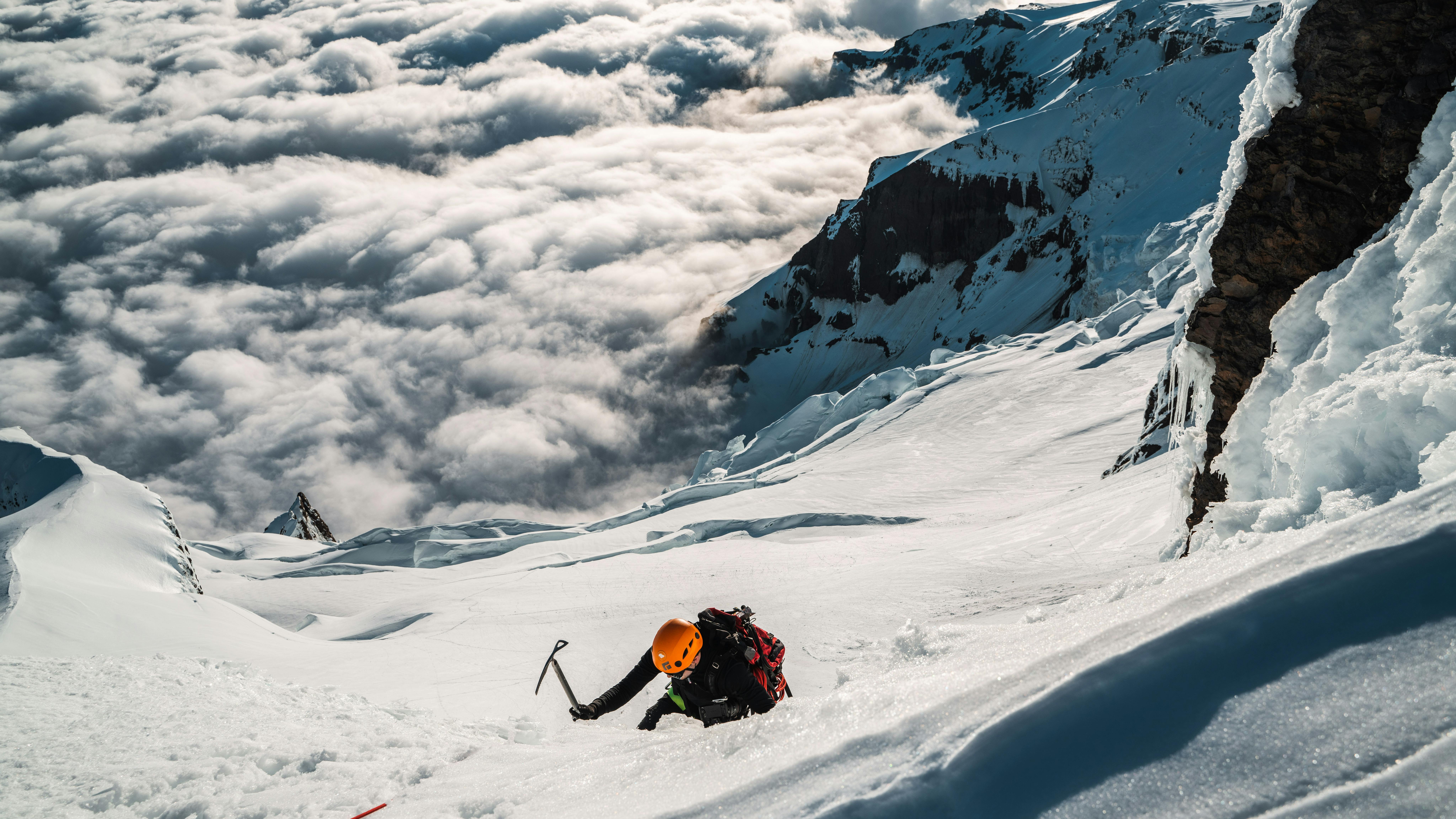 Thorsteinn Roy climbing carefully up the ridge, with the mountain and clouds in tha background