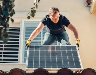 Homme qui installe des panneaux solaires sur un toit