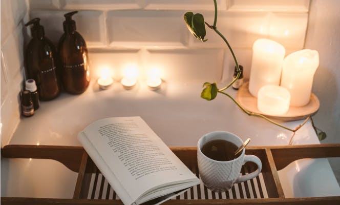 Bain chaud avec bougies, livre et tasse de thé dans une ambiance relaxante
