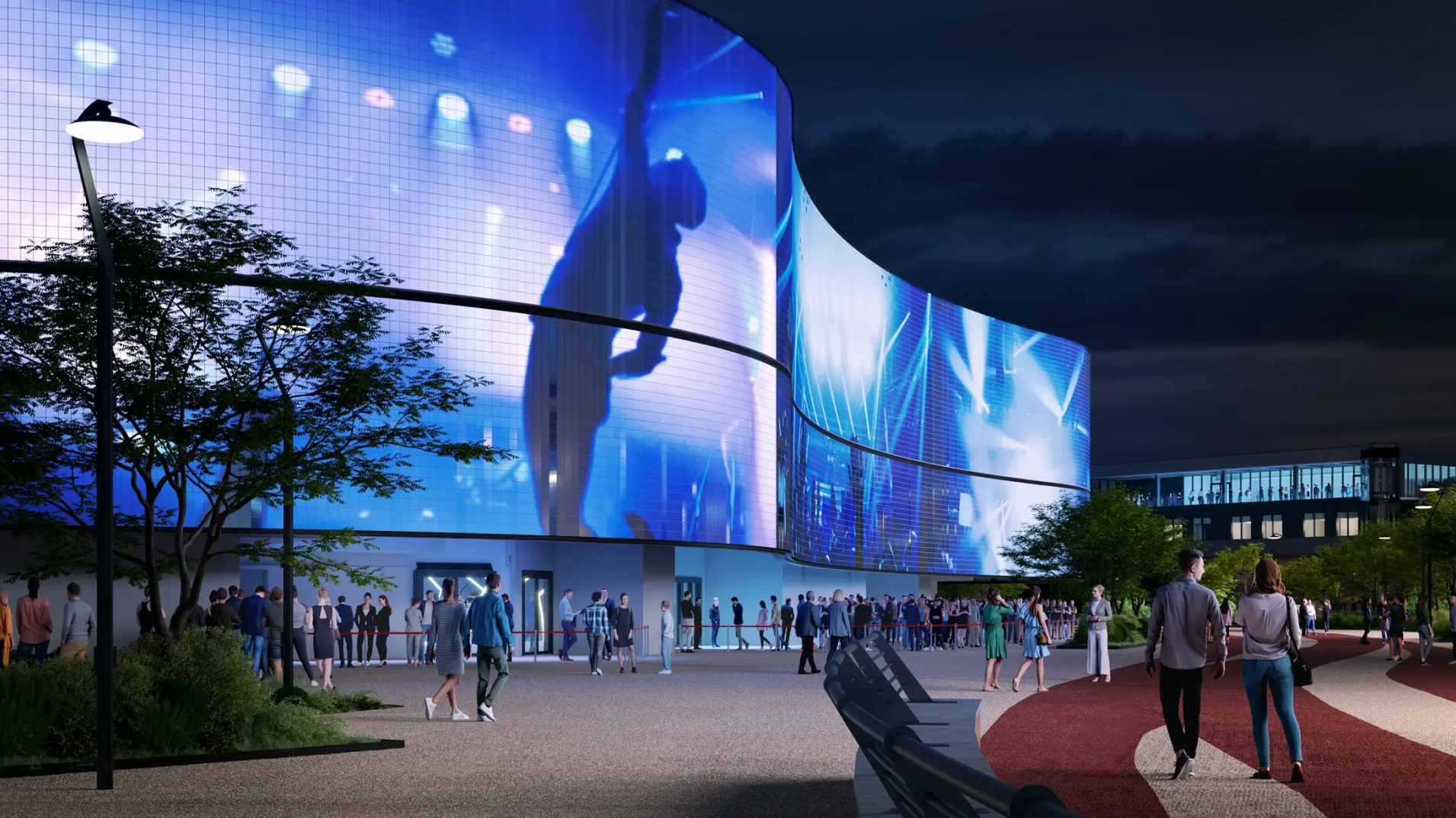 Nighttime scene of a modern arena with large, curved digital screens displaying vibrant images, as people gather outside