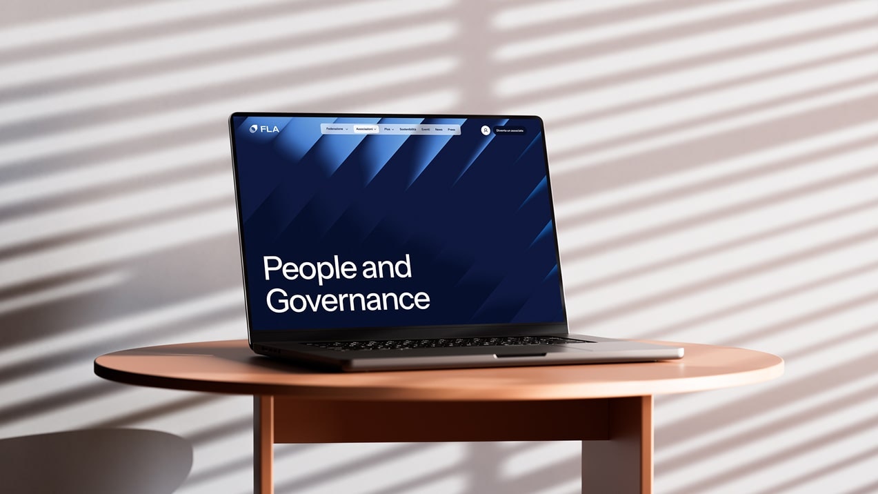 Laptop on table displaying the FLA "People and Governance" web page with blue graphics and a bright background.