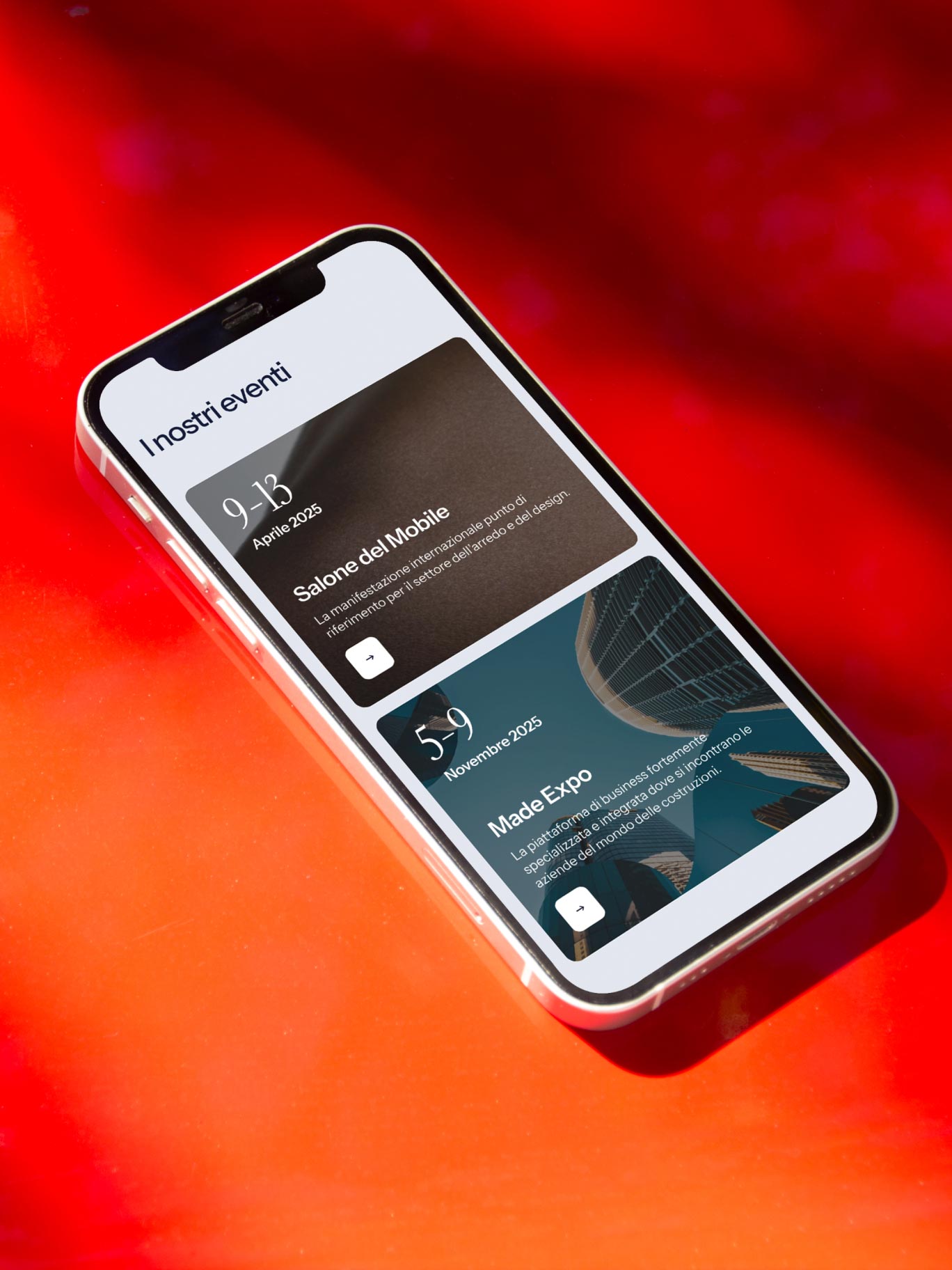Smartphone con eventi Salone del Mobile e Made Expo su sfondo rosso acceso