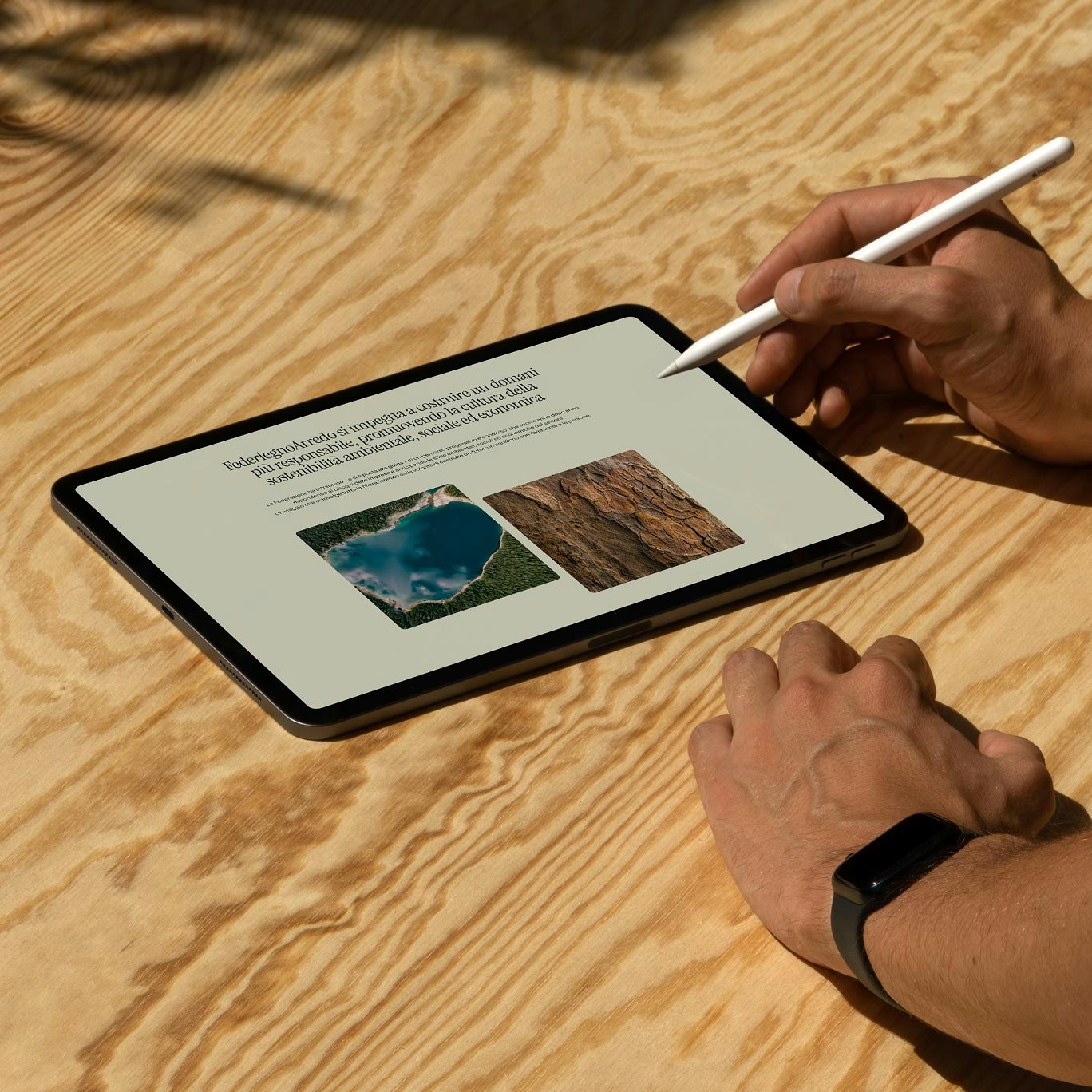 Tablet on a wooden table with FederlegnoArredo content about environmental, social, and economic sustainability.