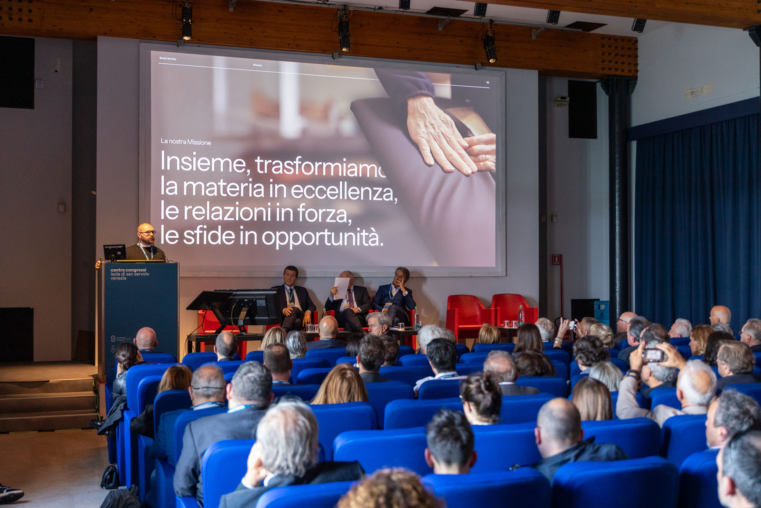 Conferenza aziendale FederlegnoArredo, con relatore che presenta la strategia 'FLA as a future catalyst' davanti a una platea di professionisti del settore legno-arredo